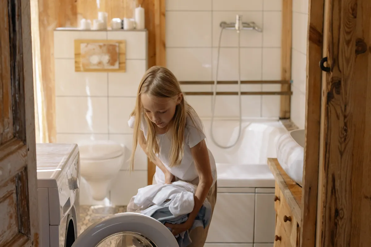 Little girl loading laundry, Is dry cleaning bad for your clothes?