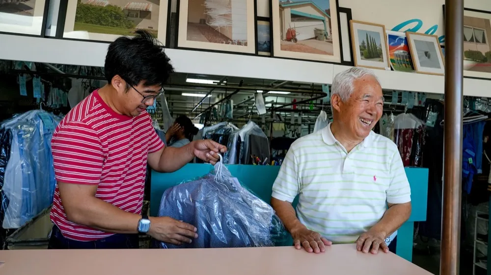 Enoch Ku and his father, Ha Wan Ku, chat with customers at Vogue Cleaners in Arden Arcade.